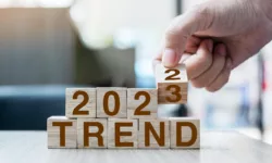 hand flipping block 2022 to 2023 TREND text on table.